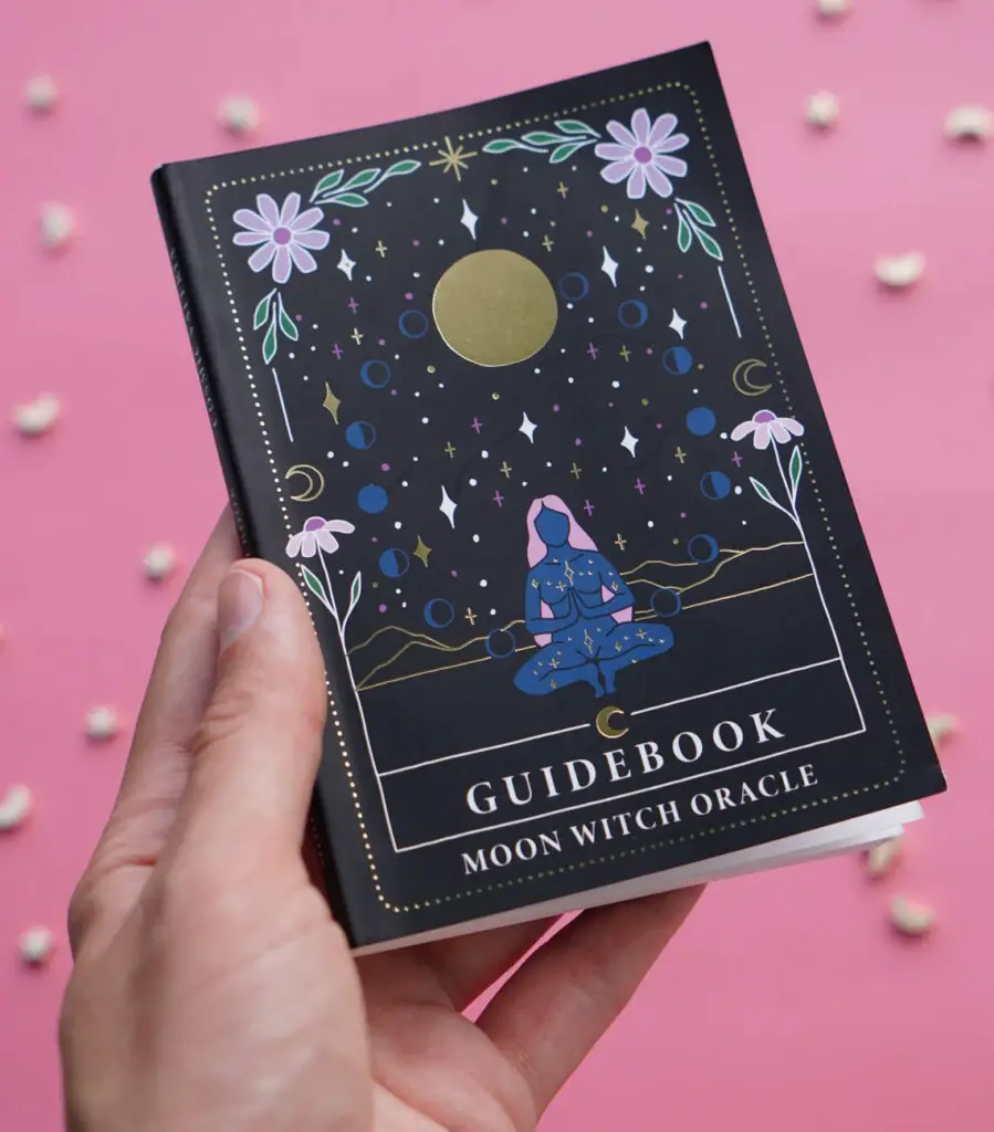 Someone holding The Moon Witch Oracle guidebook