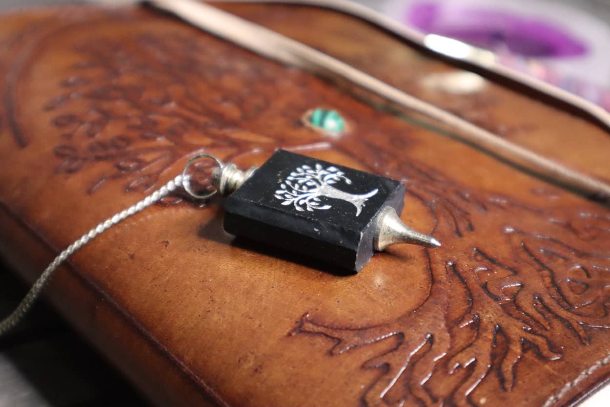 Black pendulum on wooden grimoire