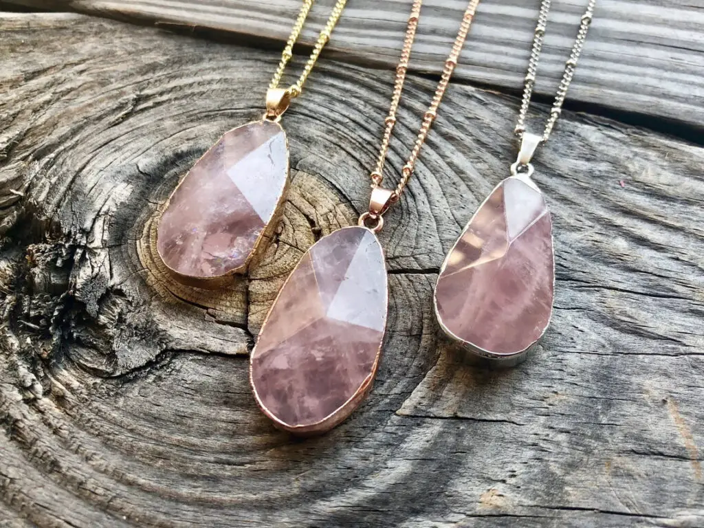 Three rose quartz pendant necklaces on wood